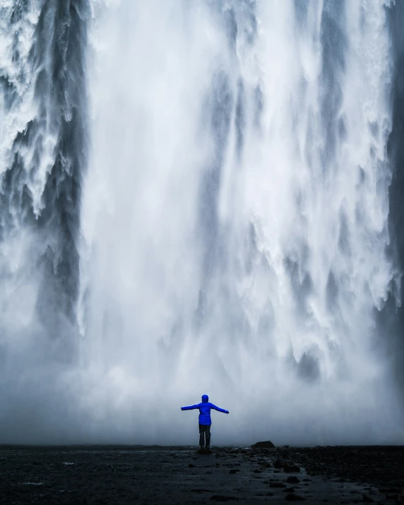 a man stands in front of a very massive waterfall