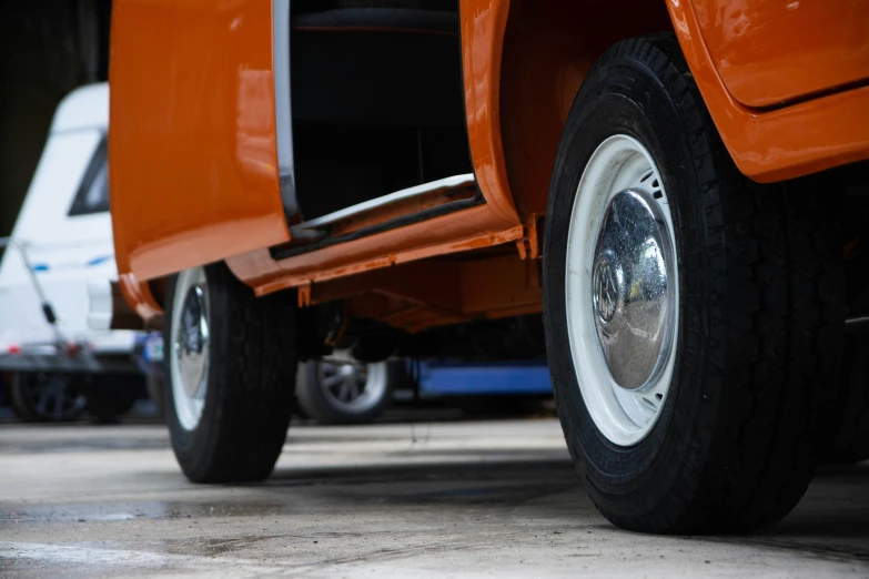 the front end of an orange truck with white rims