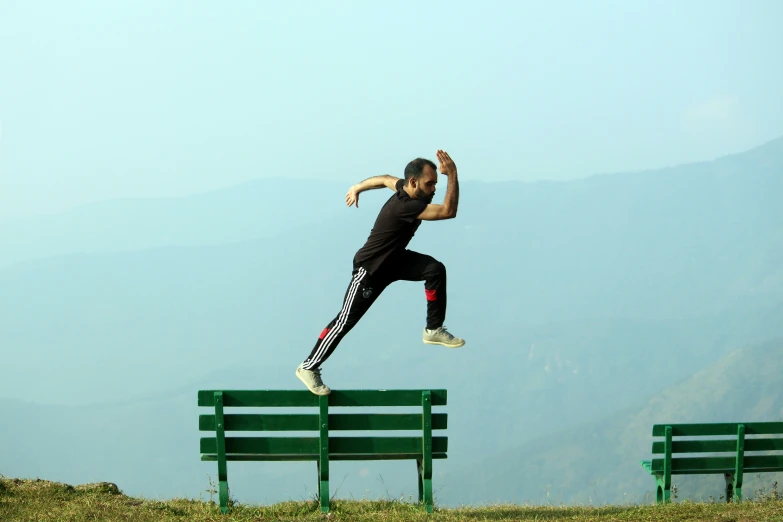 a person is jumping in the air in front of two benches