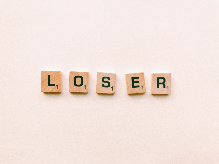 four blocks spelling the word loser against a white wall