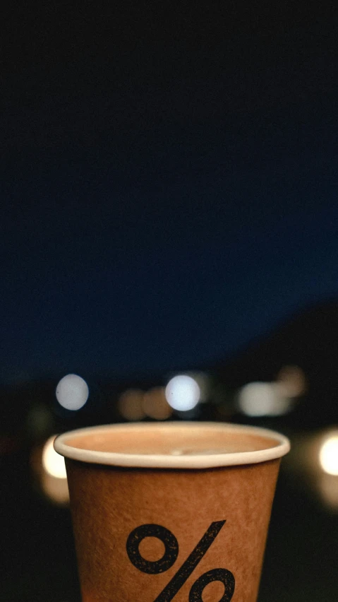 a paper cup sitting on a wooden table with a small black discount sign on it