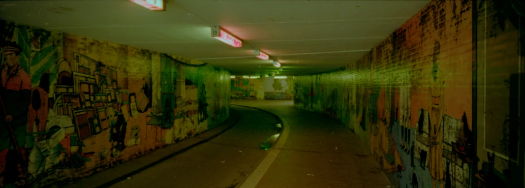 a walkway inside an underground passage covered with graffiti