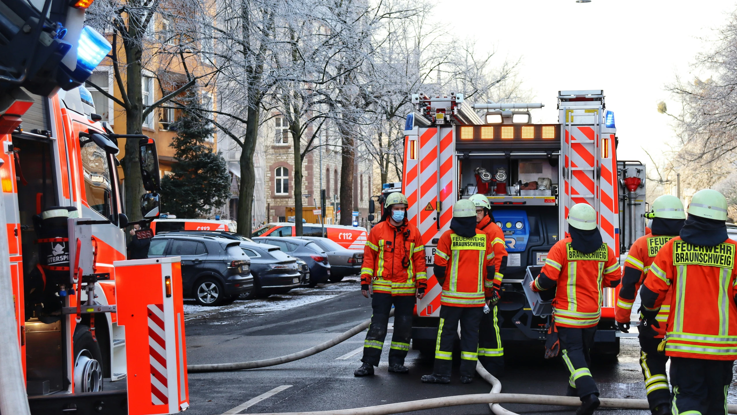 firefighters in orange jackets talking to a firetruck