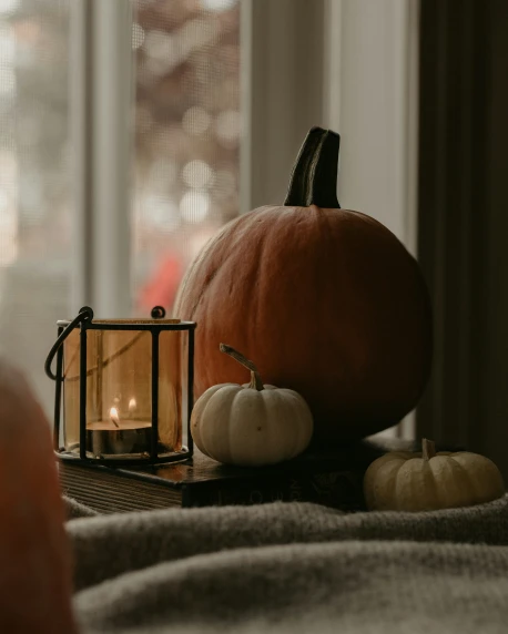 a pumpkin and some candles sit on the window sill