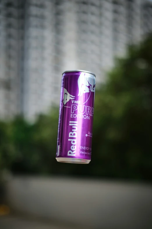 an opened purple canned drink can on a string in front of a city