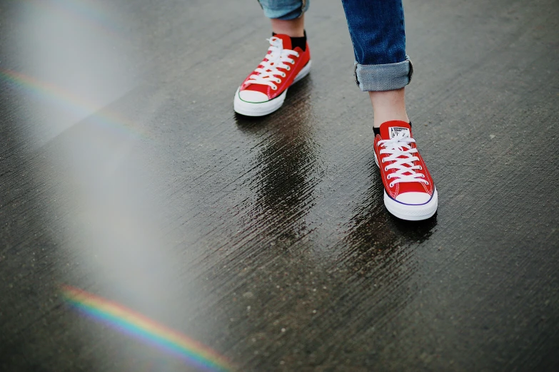 a person standing on a wet floor wearing red tennis shoes