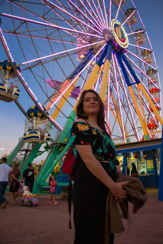 a woman posing in front of a ferris wheel