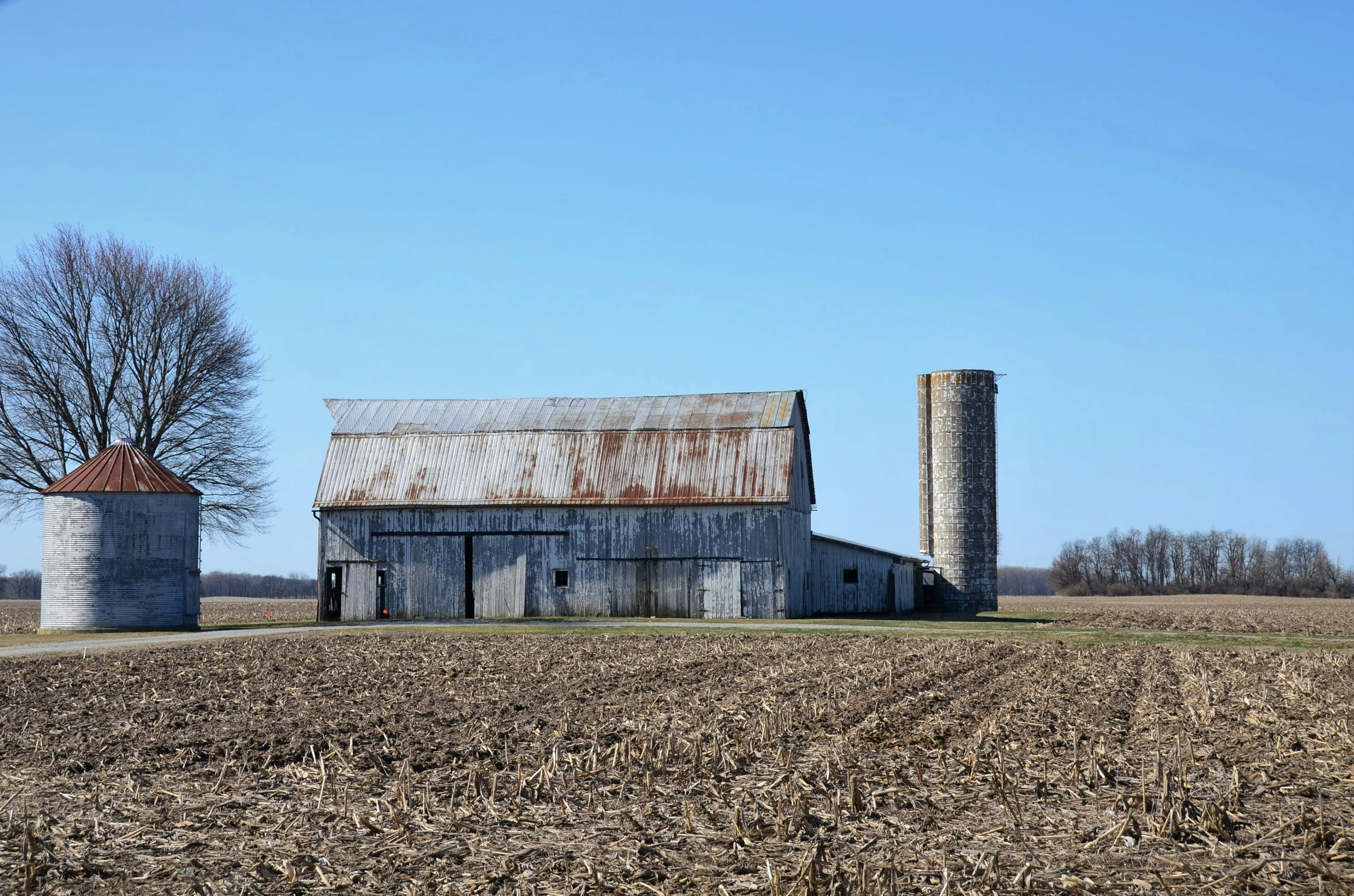 there is an old barn and silo in the middle of the field