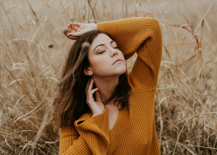 a beautiful woman in yellow sweater leaning on her head