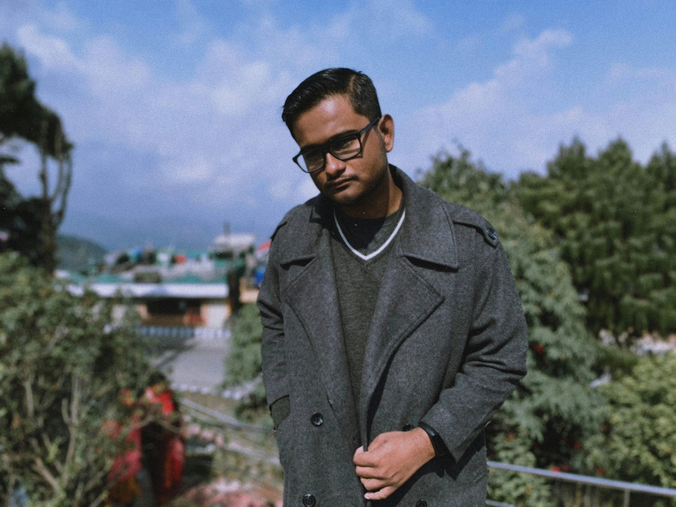 man in grey coat and black sunglasses on railing looking off to the side