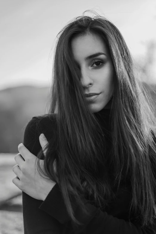 a woman with long hair standing with her arms crossed