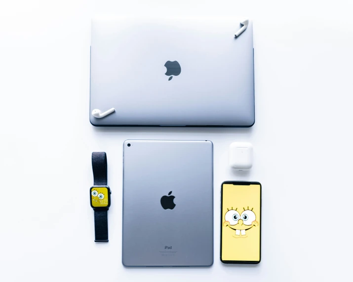 an apple laptop, and two other accessories sit on a table