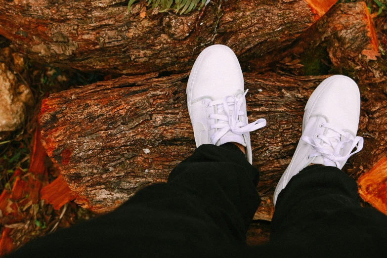 a person standing in white tennis shoes next to trees