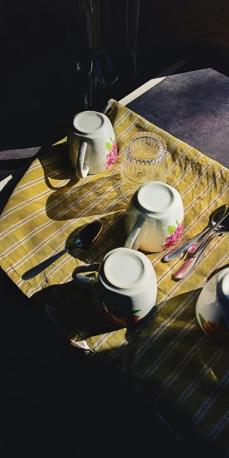 four tea pots and one tea spoon on a yellow mat