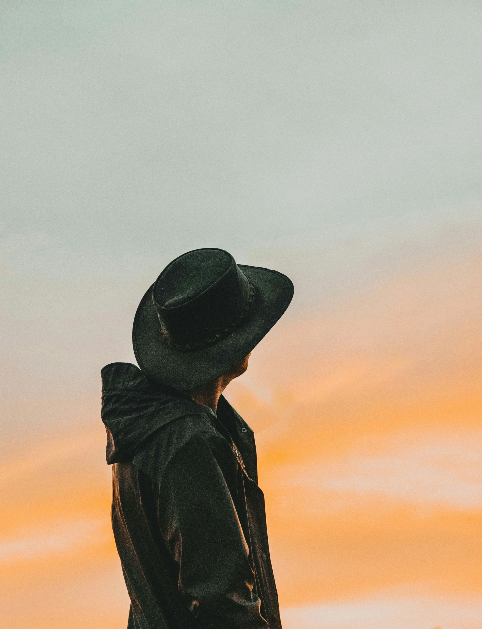 a person standing in a field while wearing a black coat