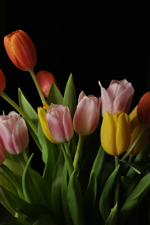 many tulips that are pink and yellow in a vase