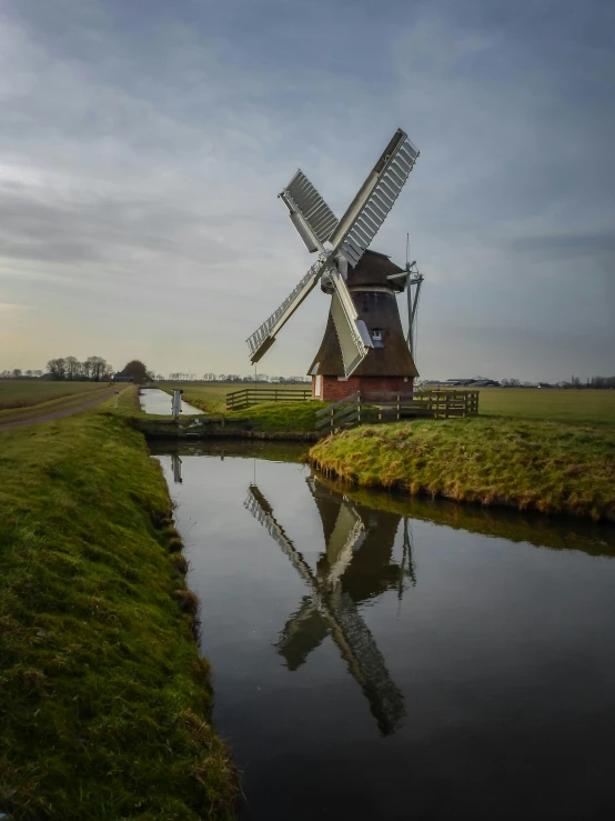 a windmill is on the other side of a canal