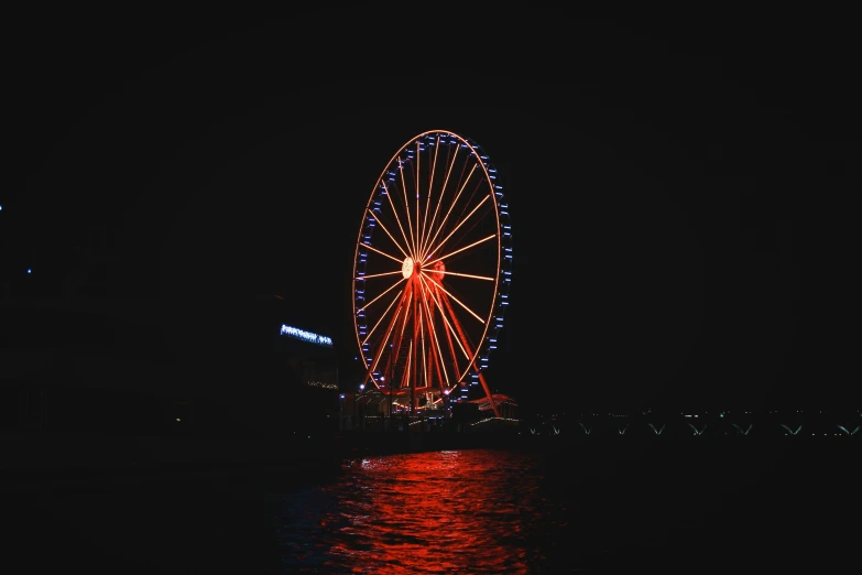 the ferris wheel shines brightly at night on the water