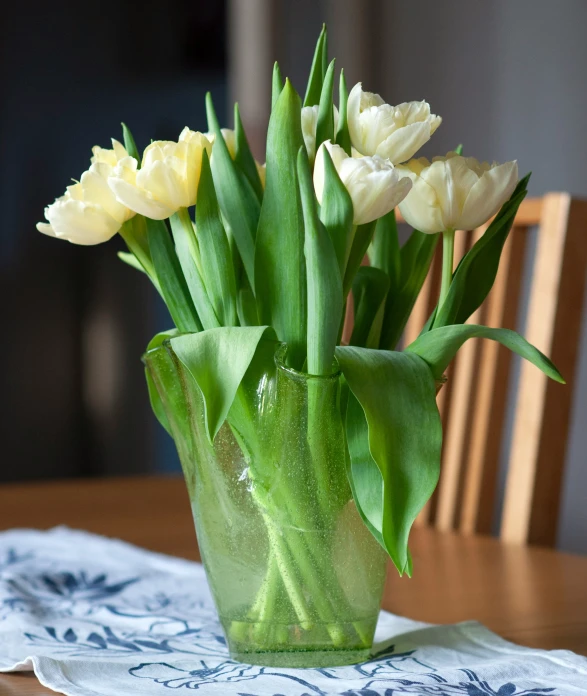 several yellow tulips sit in a vase on a table