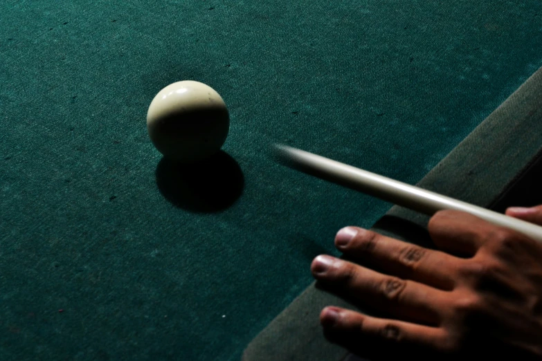 a man holding his pool cue with a white object by the pool table