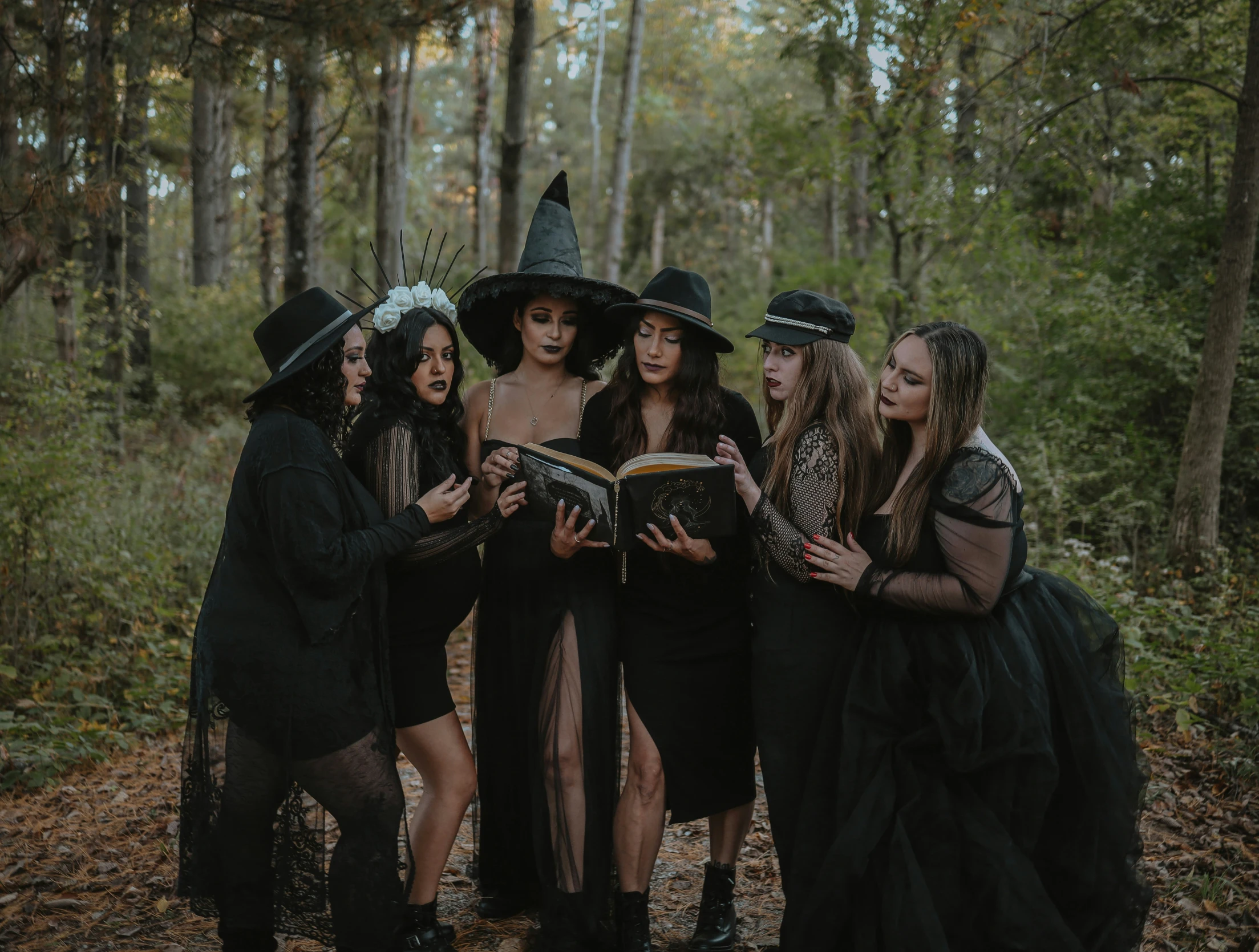 a group of women dressed as witches looking at a book