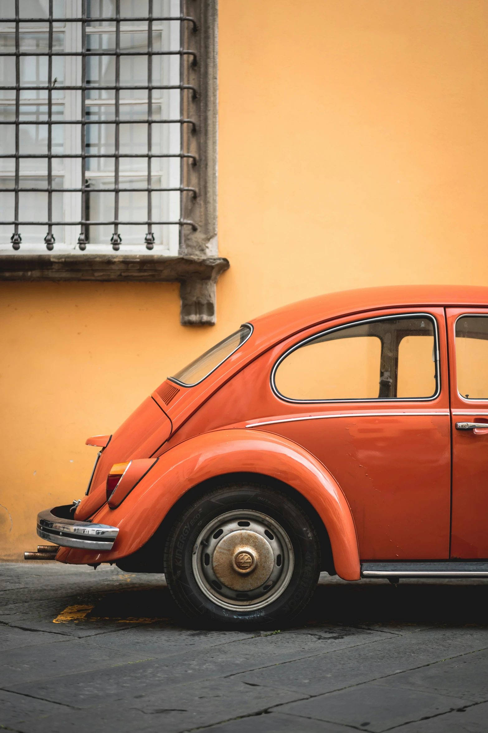 an orange volkswagen car parked in front of a building