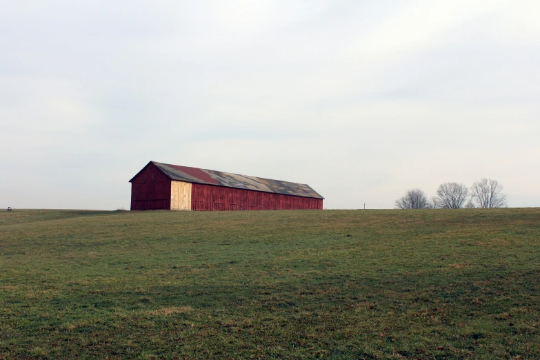 a barn in a grassy field on a cloudy day