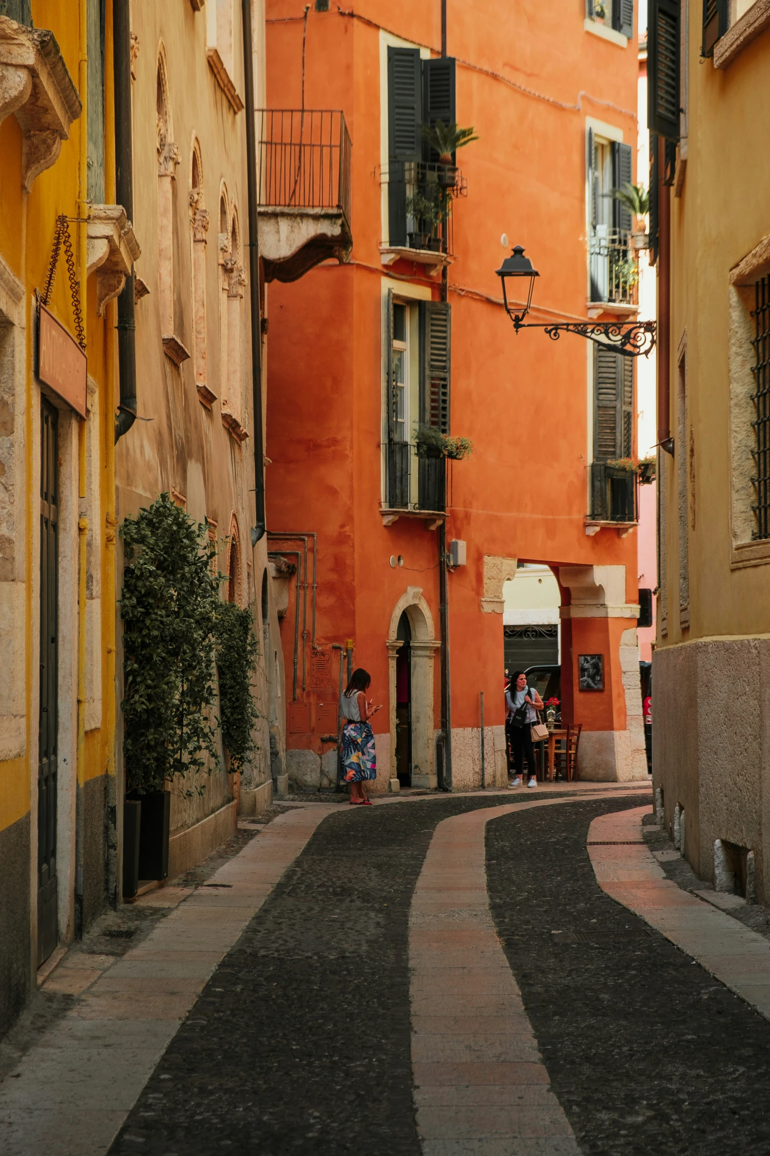 the two people are sitting on the bench in the middle of this street