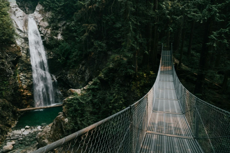 a person on a suspension bridge that has a waterfall in the background