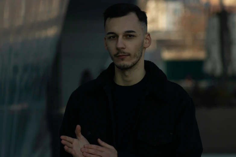 a man standing holding his hands together in front of a building