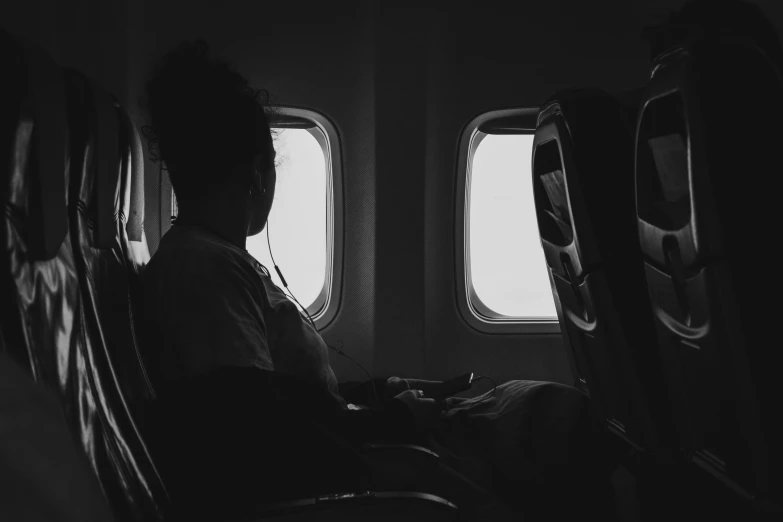 the man is sitting alone on the seat in front of the window