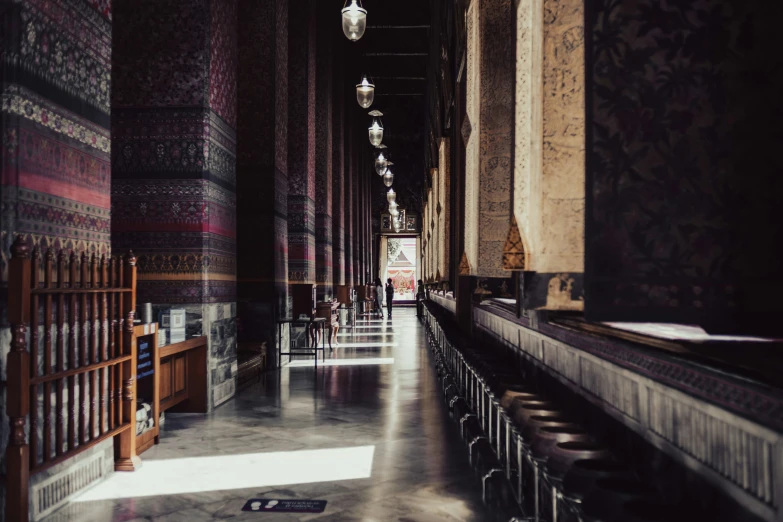 a hallway with a number of benches and lamps hanging from the ceiling