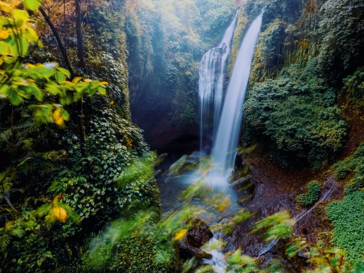 large waterfall on top of a mountain surrounded by lush green jungle