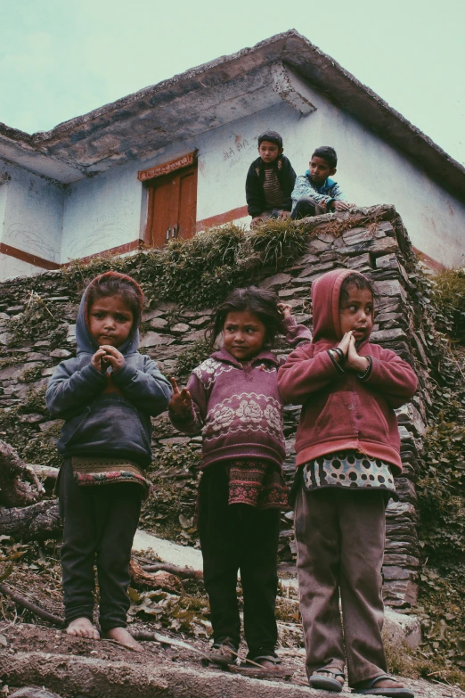 three little children are standing on the roof of a house