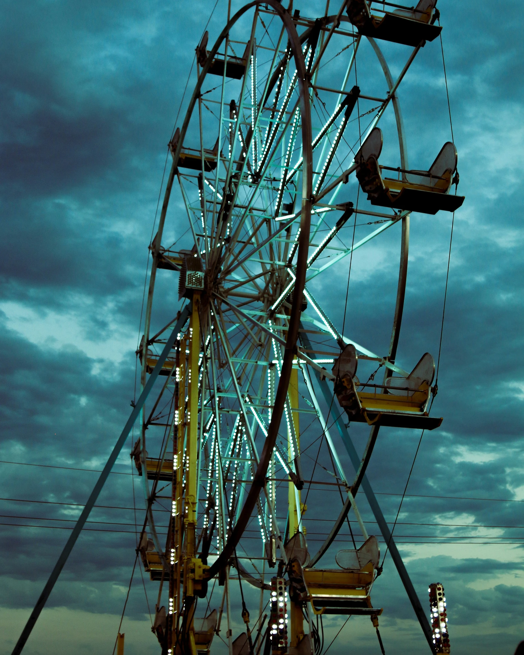 the ferris wheel is parked under the cloudy sky