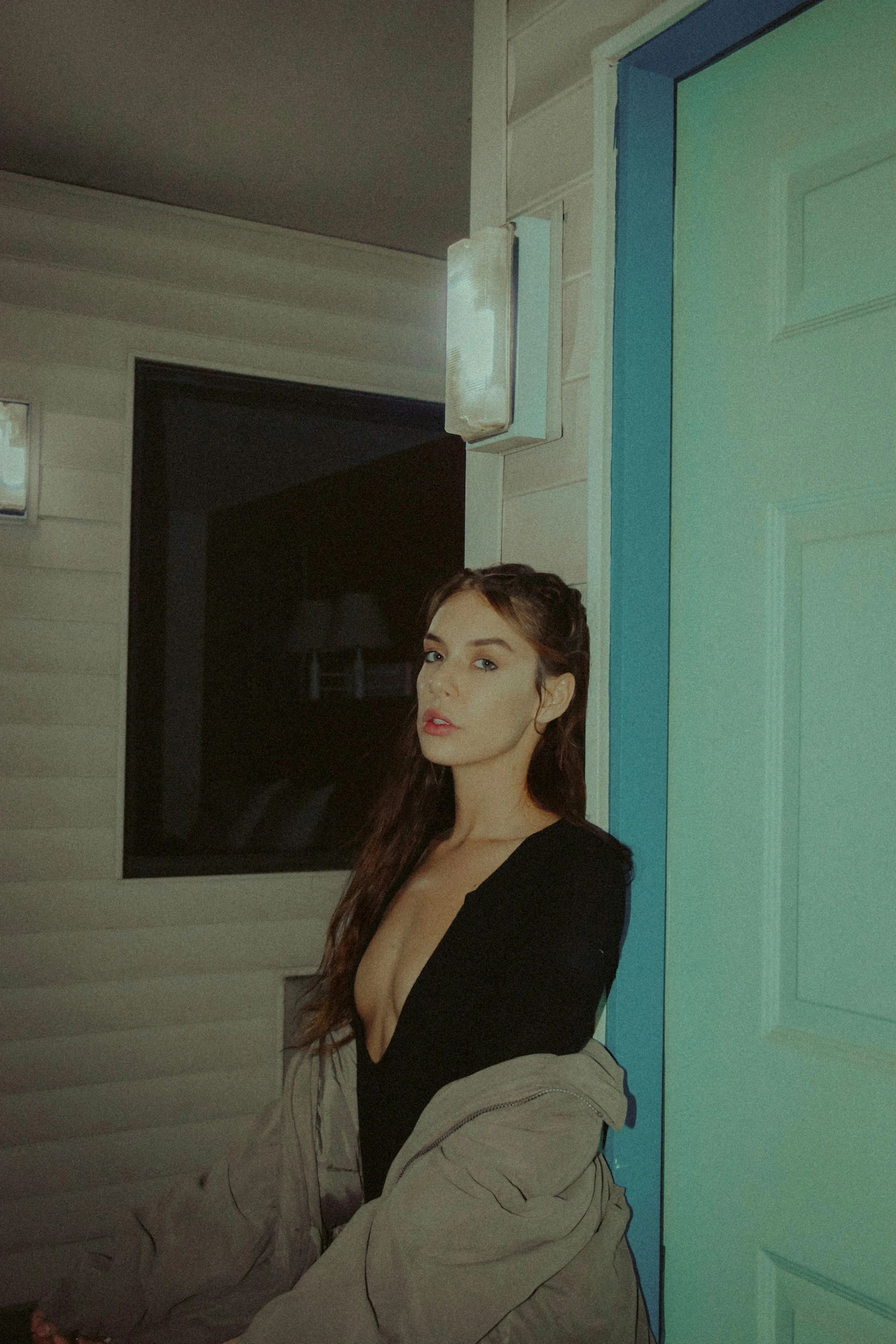 a girl posing near the blue door with her jacket on