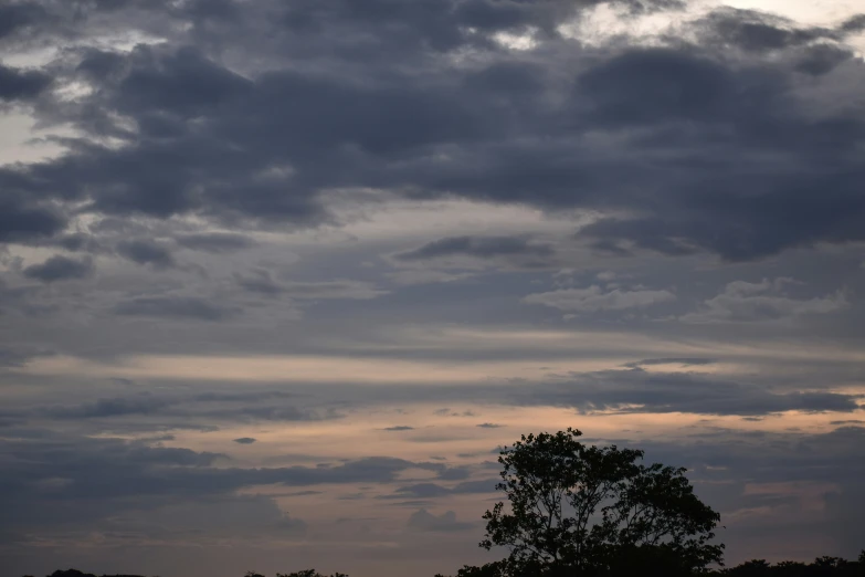 a large plane flying through the cloudy sky