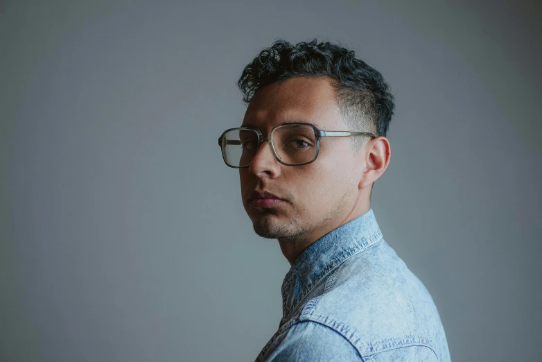 man with curly hair, glasses and denim shirt