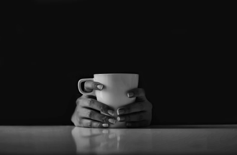 black and white pograph of a person holding a coffee cup