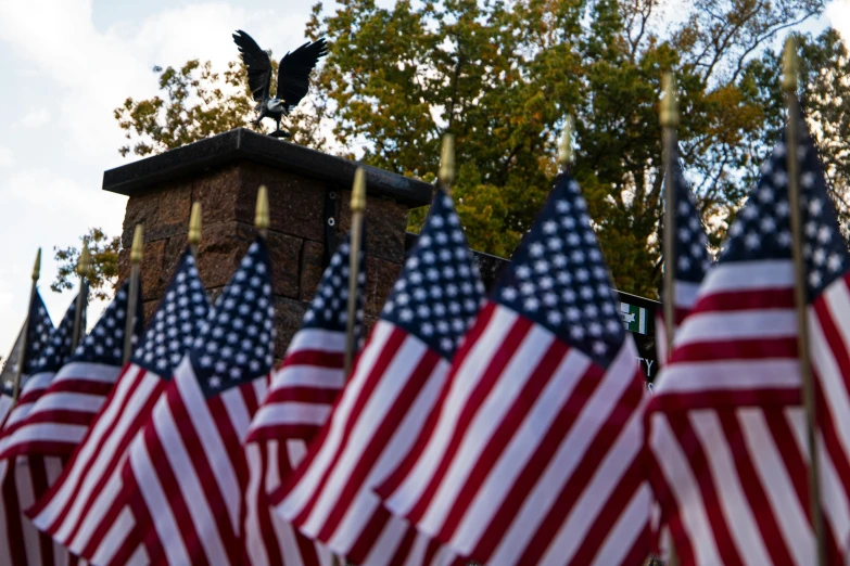 a bird on top of a tower made of small american flags