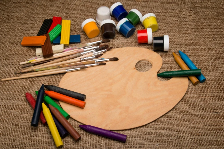 a wooden tray with a paintbrush and a variety of crayons on it