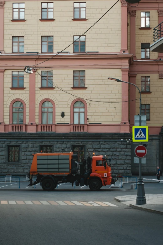 an orange truck parked in front of a large brick building