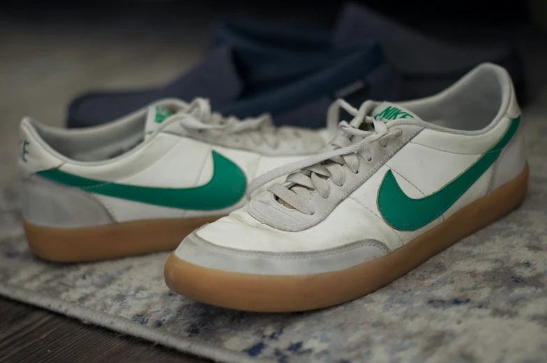 a pair of green and white sneakers on top of a mat