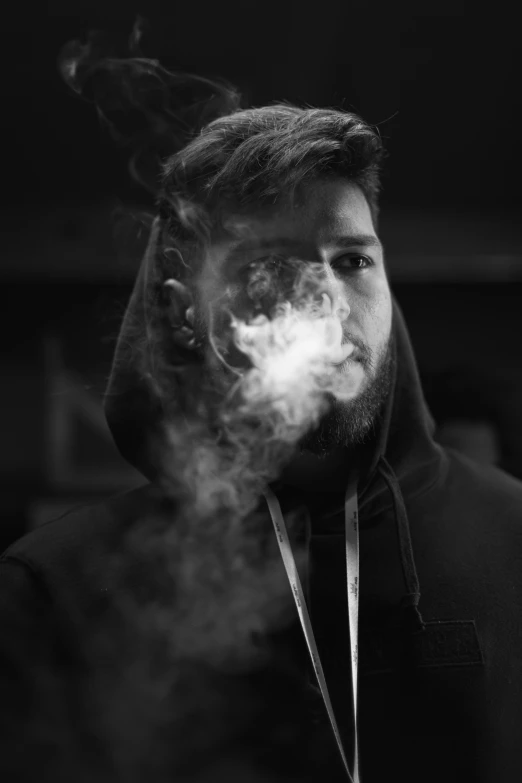 a man in a black hoodie has smoke coming out of his face