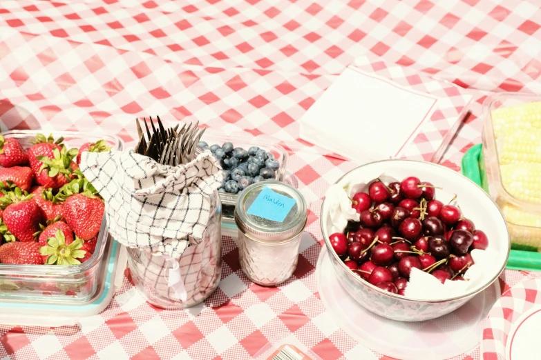 a red and white table topped with bowls of cherries and fruit