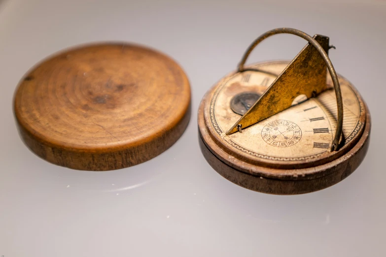 an antique pocket compass and wooden stand are on a table