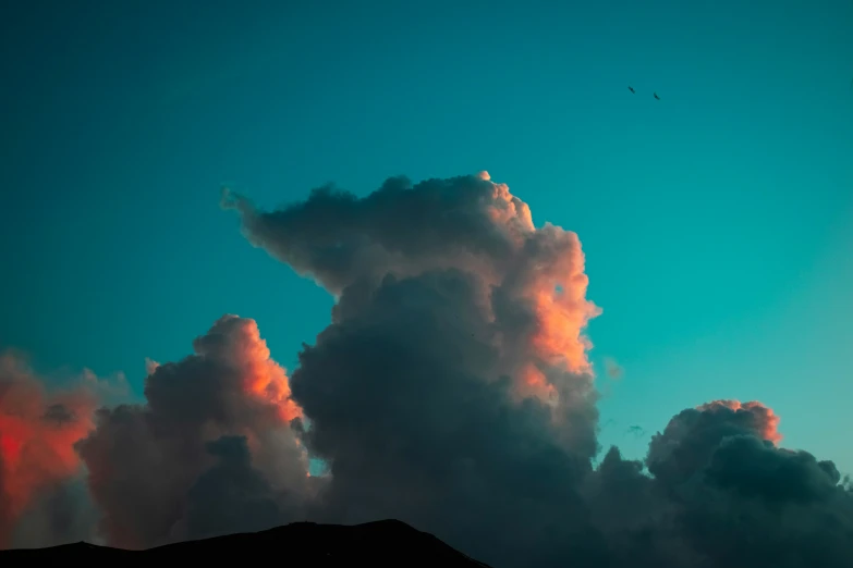 a bright red cloud rises above a mountain side