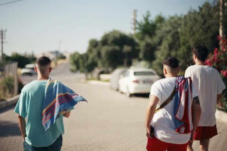 two men walking down the road holding onto towels
