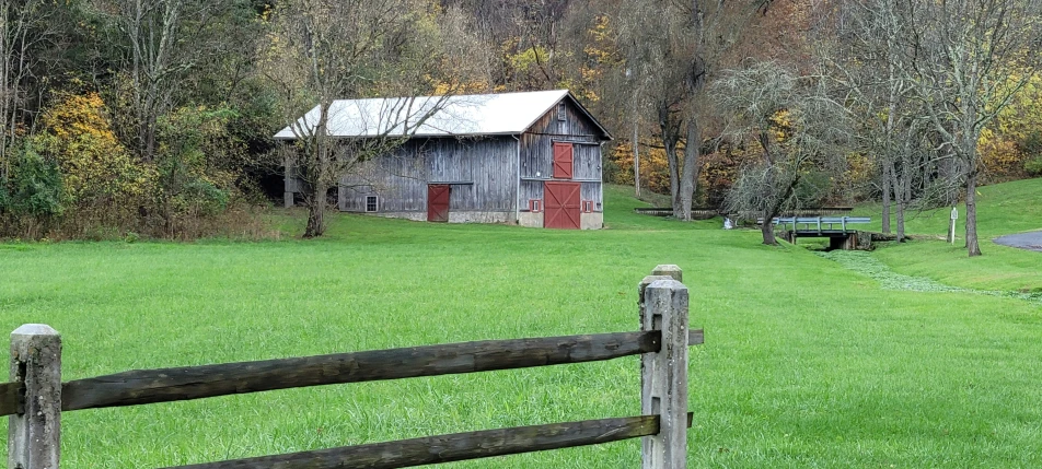 an old barn stands in a pasture with an overhang