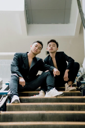 two men sitting on top of stairs looking at soing